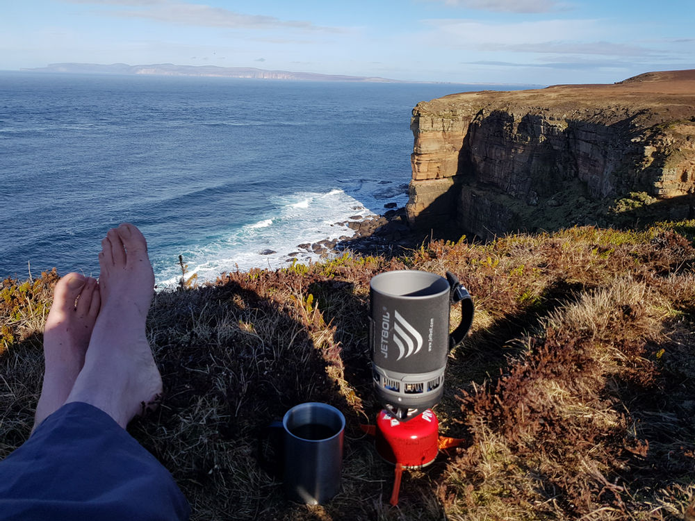 John O'Groats Staff member sitting at the top of the stacks near John O'Groats on their hike
